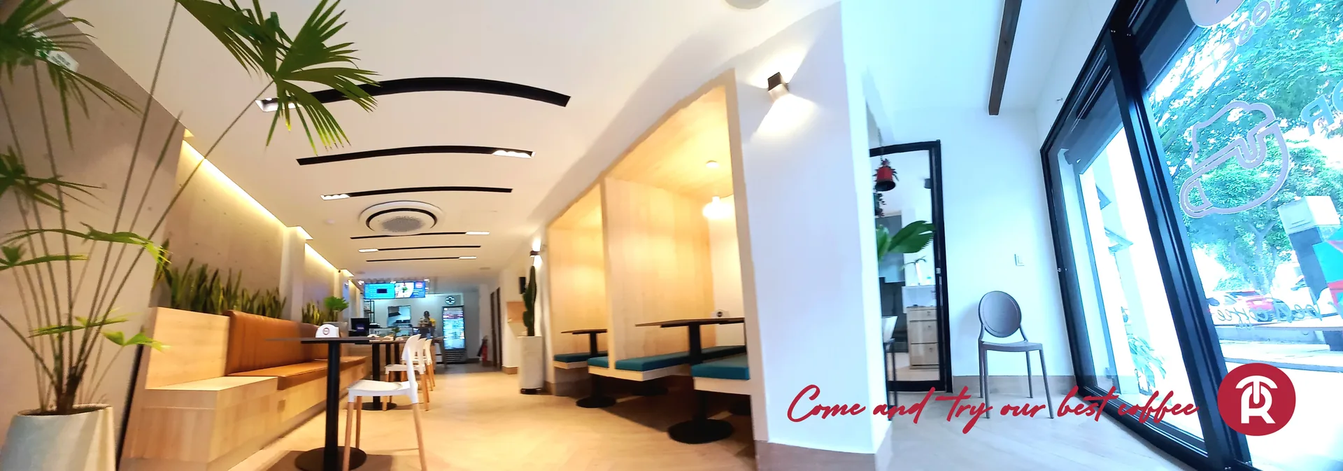 Interior del café Reset con mesas, asientos tipo cabina y plantas